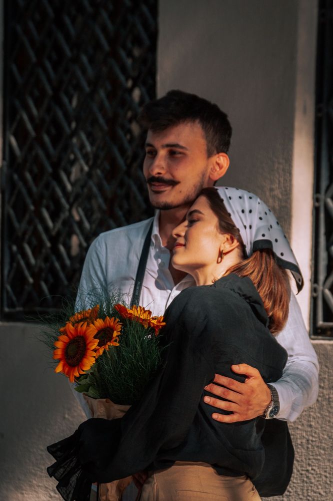A couple embracing with a bouquet of sunflowers